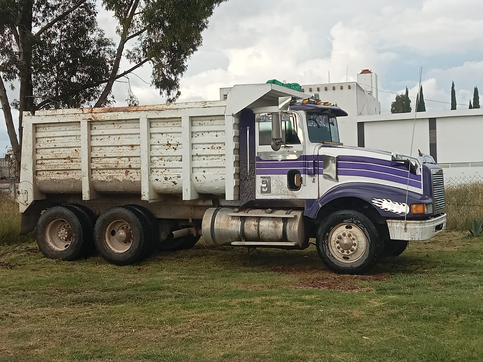 Camión de volteo blanco con franjas moradas